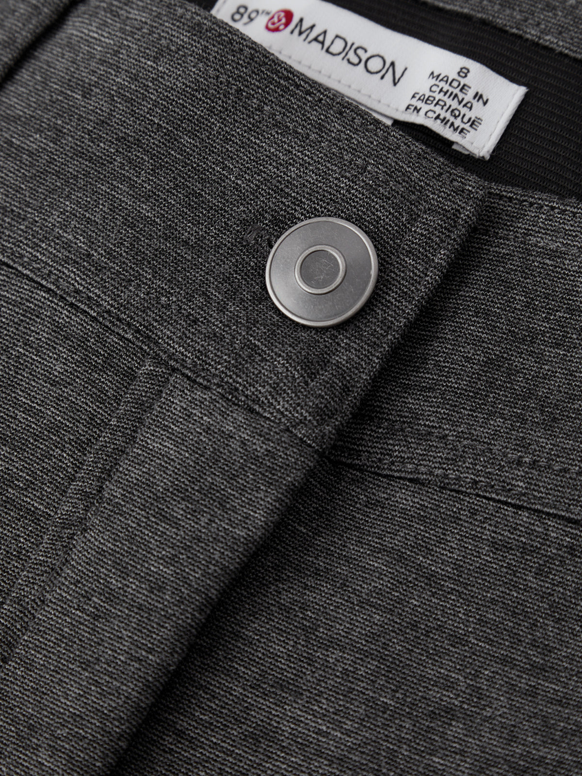 Close-up of a gray garment with a label and button detail