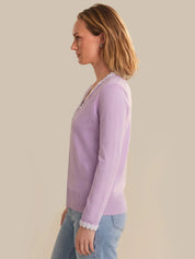 Woman wearing a light purple long-sleeve shirt against a beige background