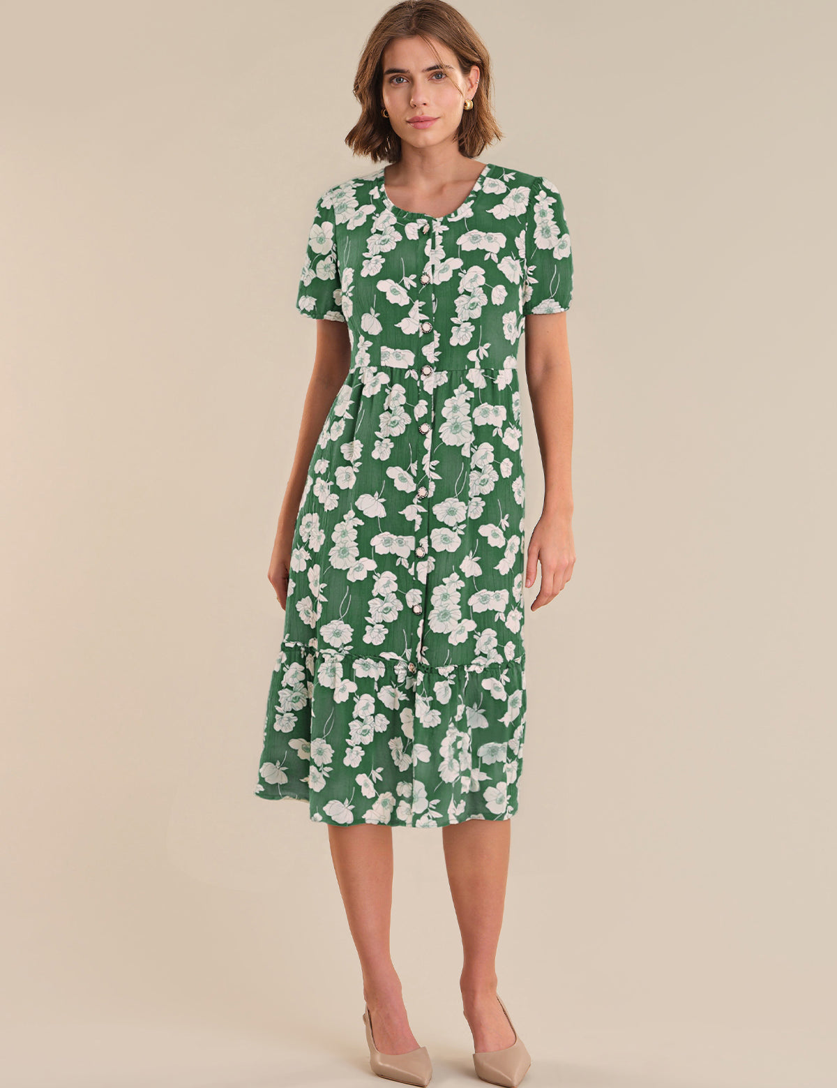 Woman wearing a green floral dress on a beige background