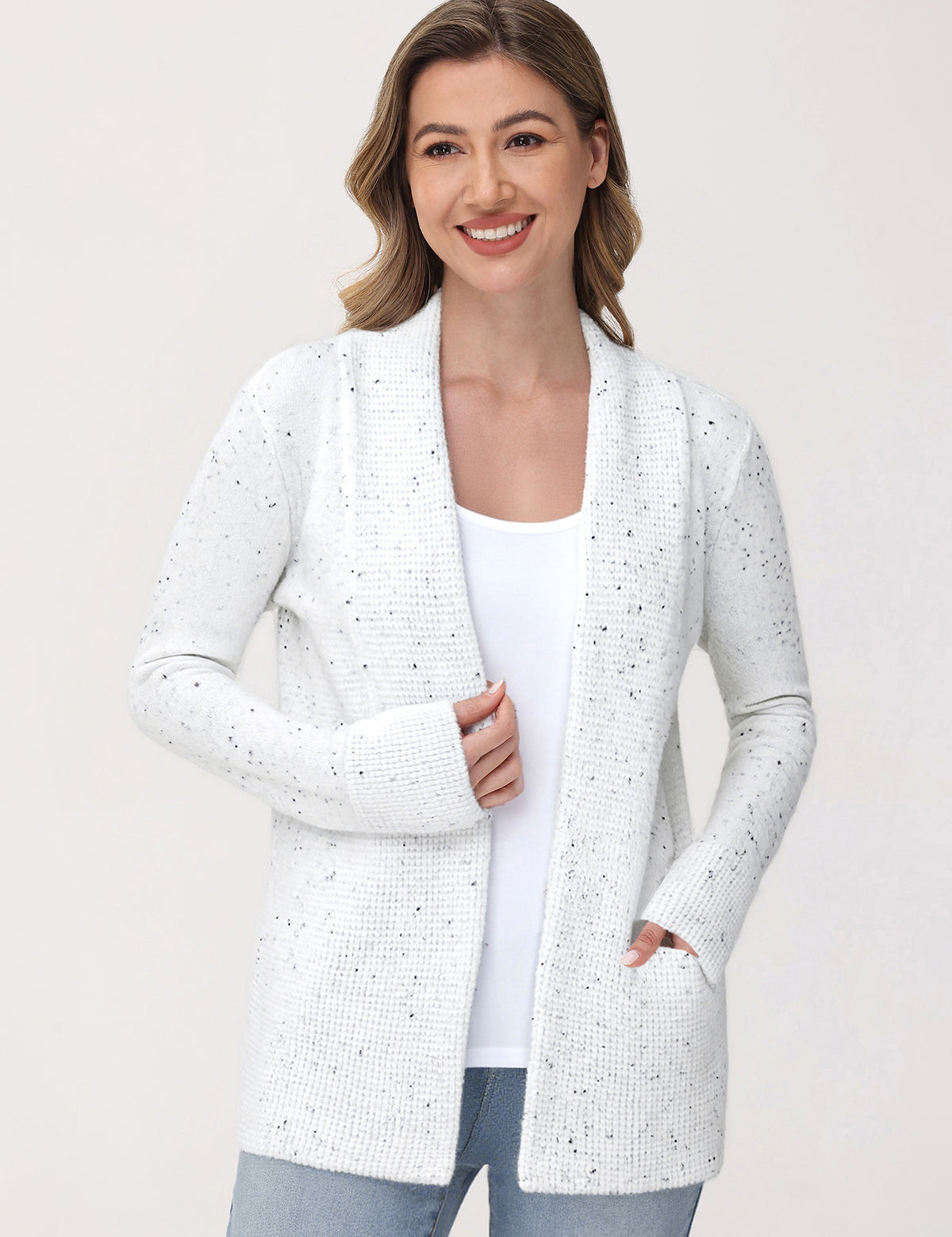 Woman wearing a white cardigan with a subtle pattern on a plain background