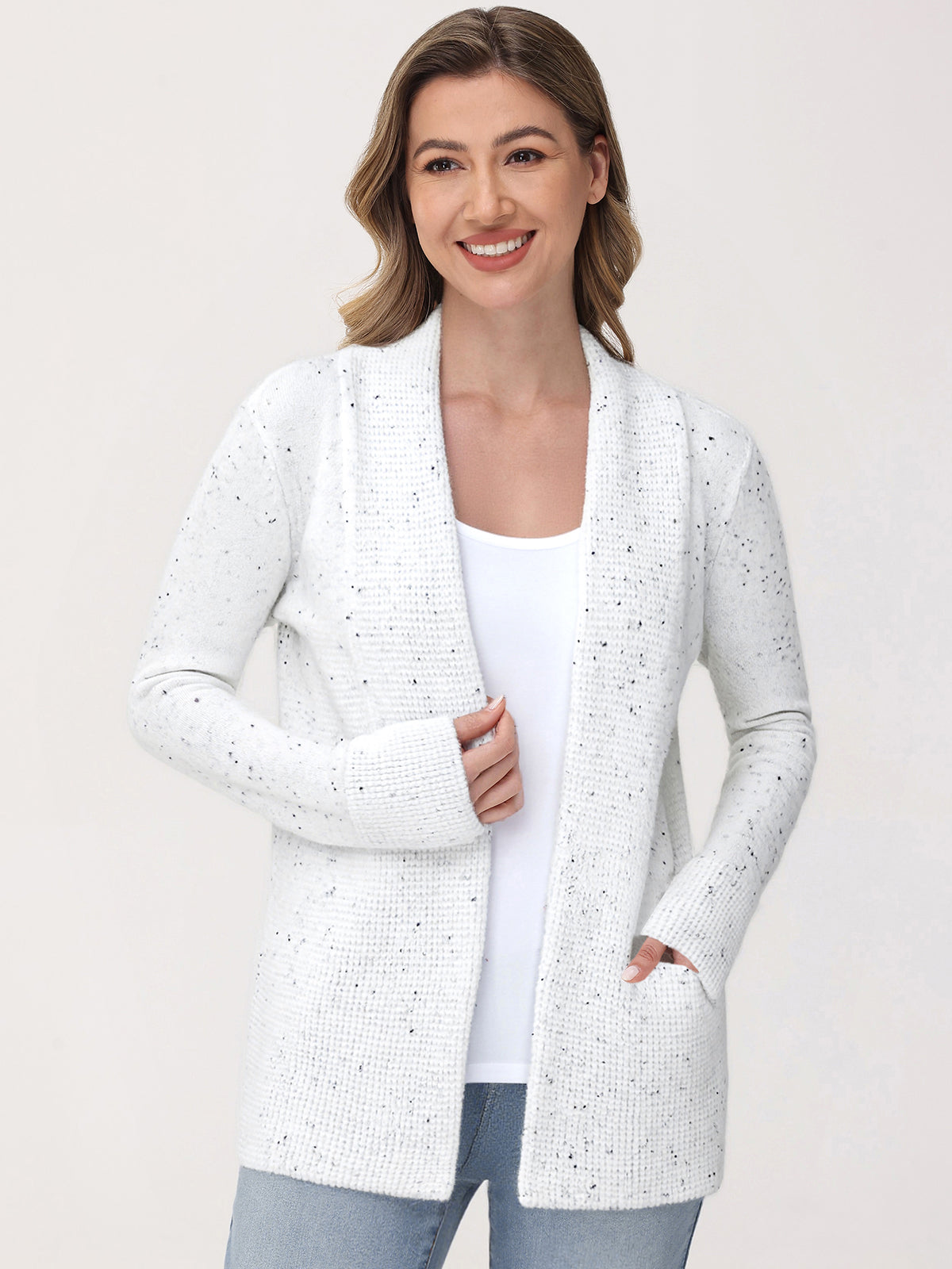Woman wearing a white cardigan with a subtle pattern on a plain background