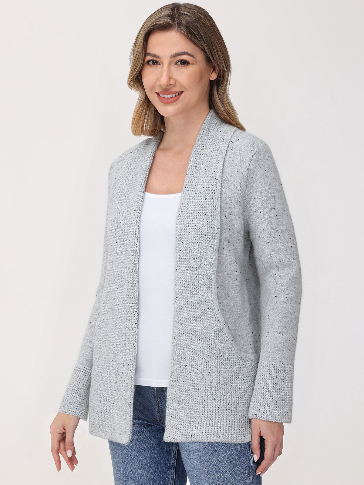 Woman wearing a gray textured cardigan over a white top and blue jeans on a white background