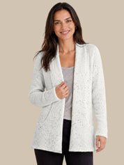 A woman modeling a light white open-front cardigan with subtle black speckles, worn over a gray top and black pants, against a solid beige background.