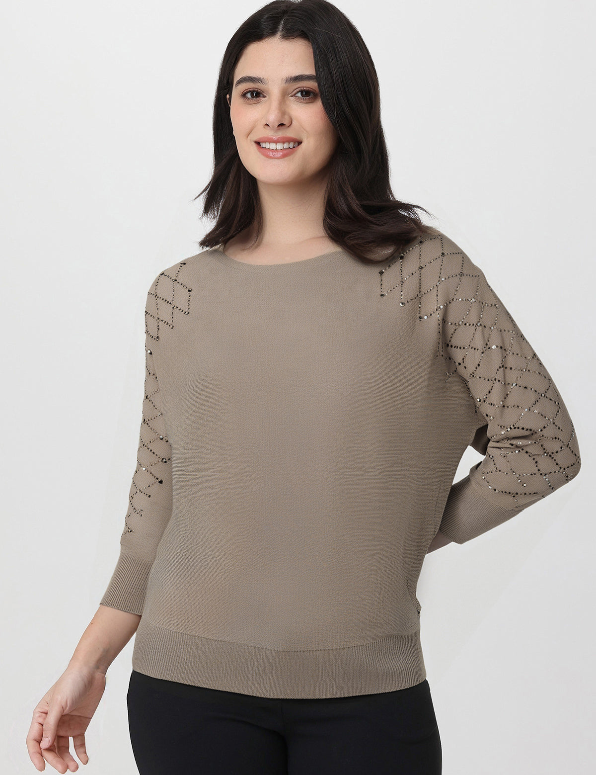 Woman wearing a beige sweater with rhinestone sleeves on a white background