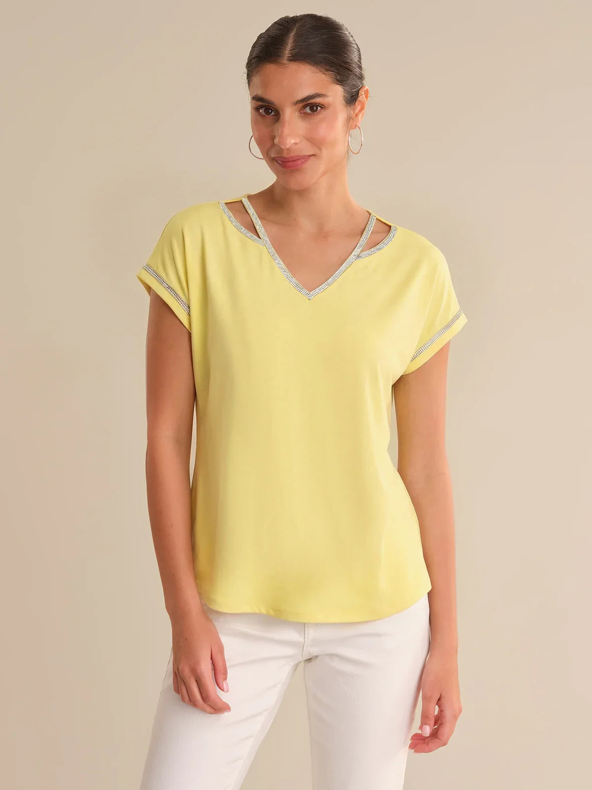 Woman wearing a yellow top with lace trim on a beige background