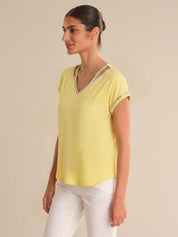 Woman wearing a yellow top with a beige background