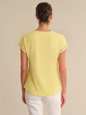 Person wearing a yellow top and white pants on a beige background
