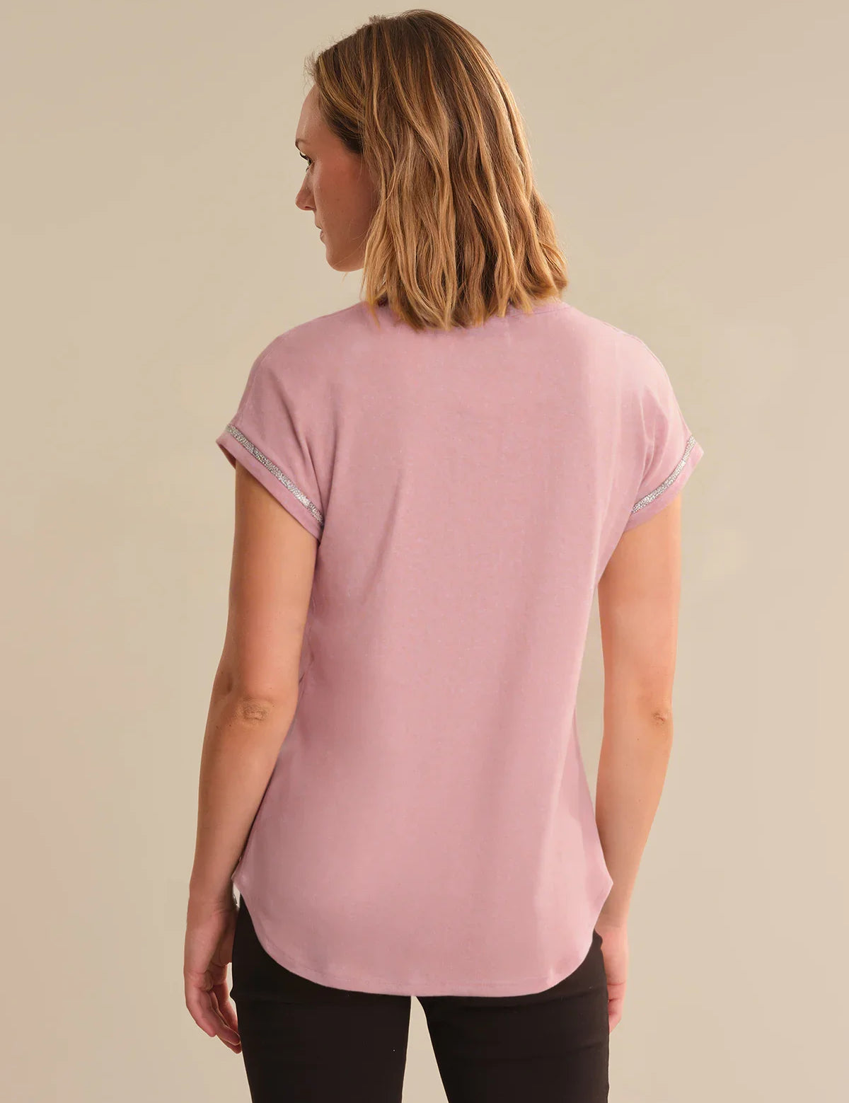 Woman wearing a pink t-shirt against a beige background