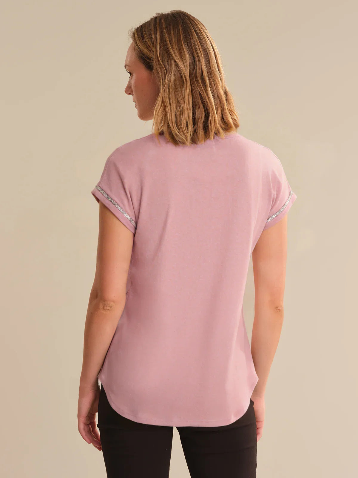 Woman wearing a pink t-shirt against a beige background