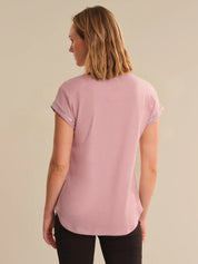 Woman wearing a pink t-shirt against a beige background