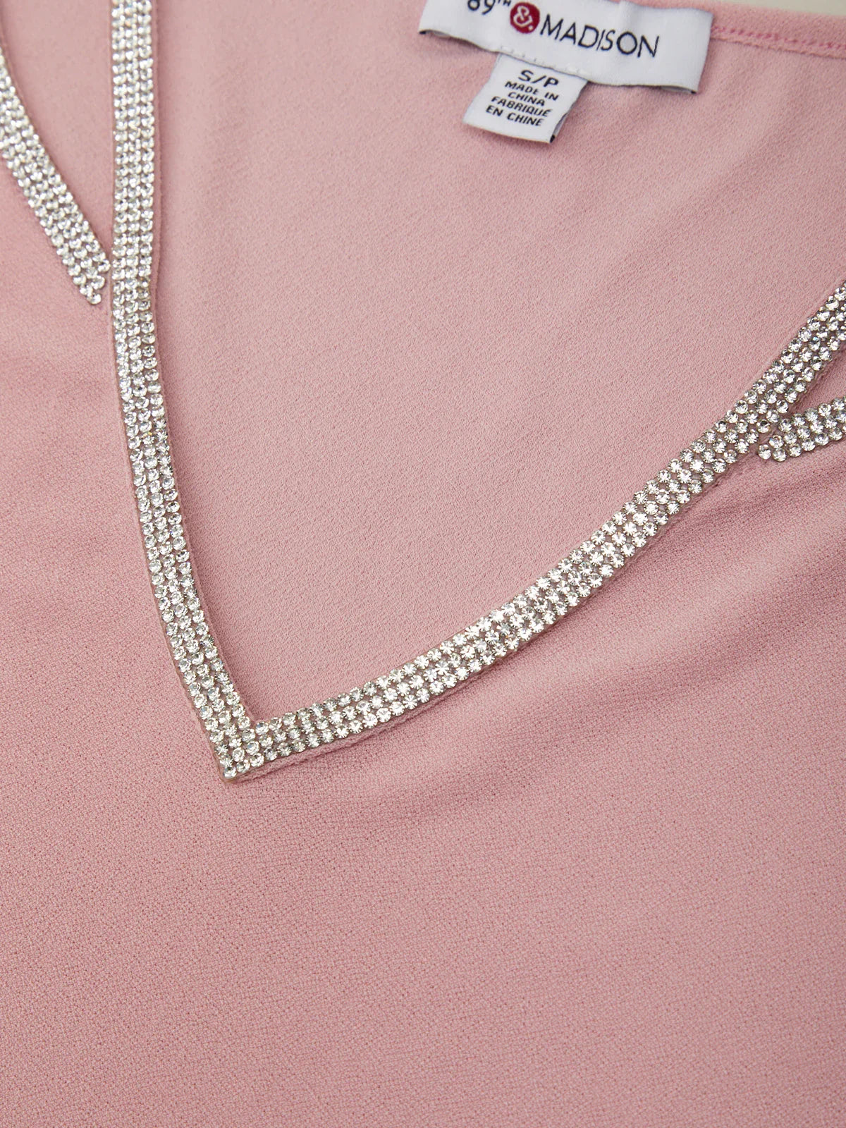 Pink garment with a decorative neckline featuring rhinestones, branded 'S.P. & MADISON'.