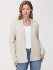 Woman wearing a beige cardigan over a white shirt and blue jeans on a white background