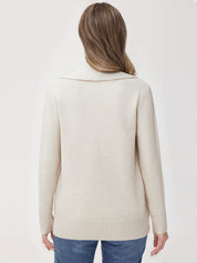 Woman wearing a beige sweater and blue jeans on a white background