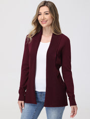 Woman wearing a burgundy cardigan over a white top and blue jeans on a white background