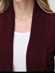 Close-up of a person wearing a burgundy cardigan over a white top.