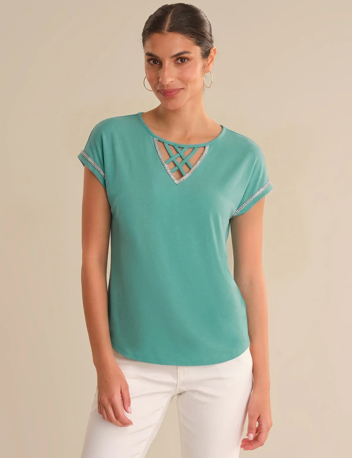 Woman wearing a teal top with a cut-out design on a beige background