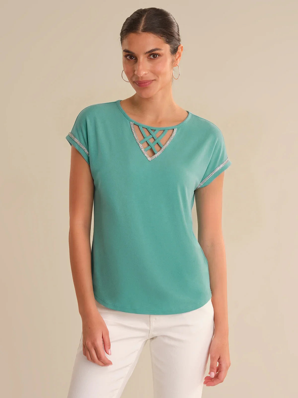 Woman wearing a teal top with a cut-out design on a beige background