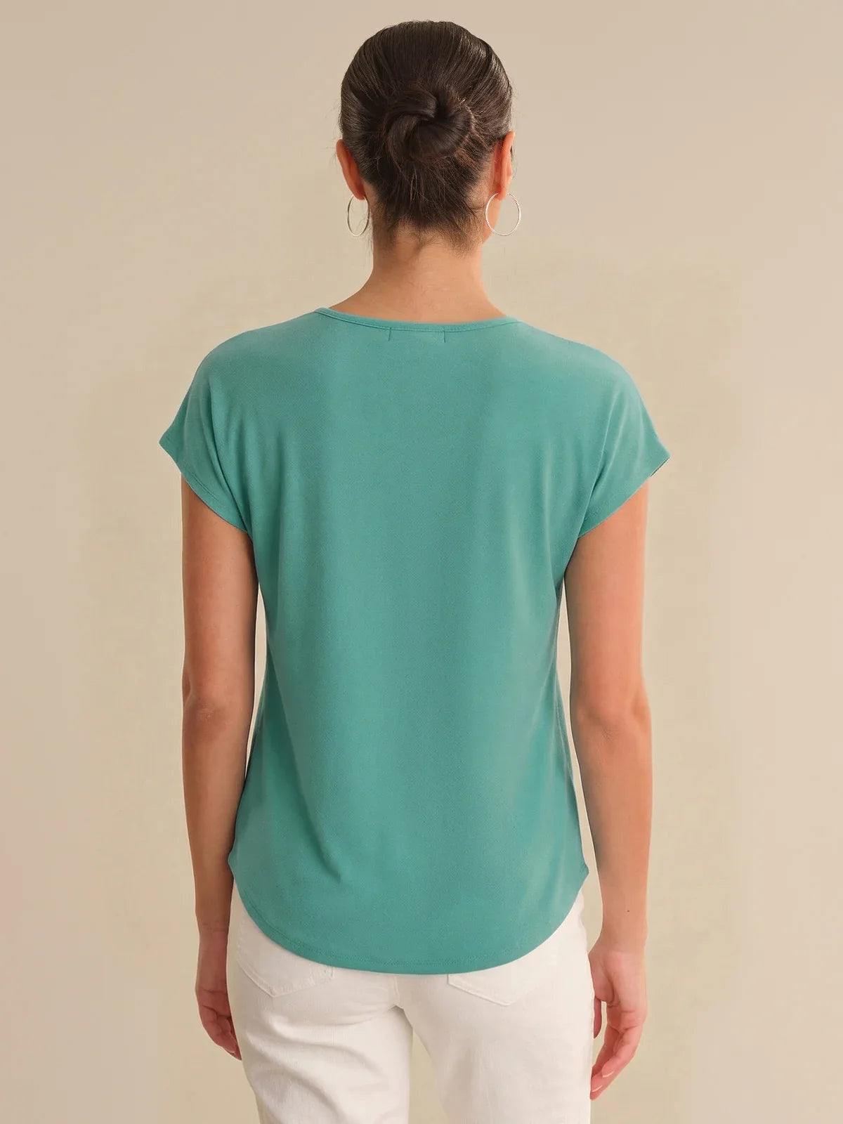 Person wearing a teal t-shirt on a beige background