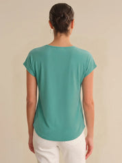 Person wearing a teal t-shirt on a beige background