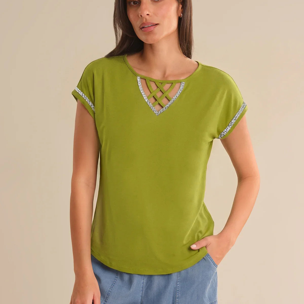 Woman wearing a green top with decorative neckline against a beige background