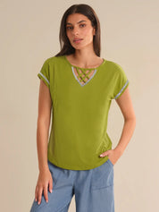 Woman wearing a green top with decorative neckline against a beige background