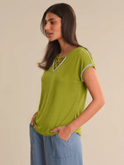 Woman wearing a green top with lace details on a beige background