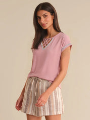 Woman wearing a pink top with lace details and a striped skirt on a beige background