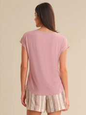 Woman wearing a pink t-shirt and patterned shorts on a beige background