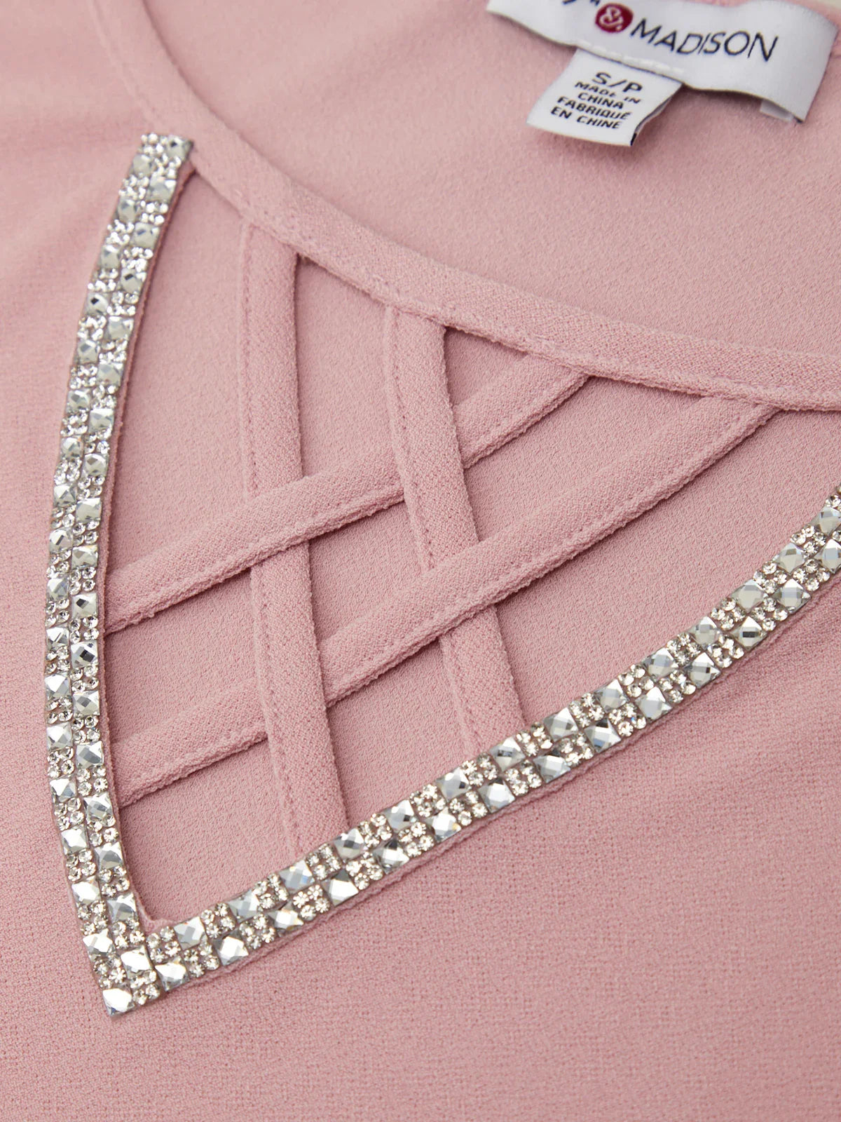 Close-up of a pink garment with a decorative crystal border and a visible label.