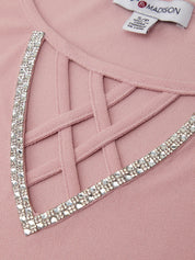 Close-up of a pink garment with a decorative crystal border and a visible label.
