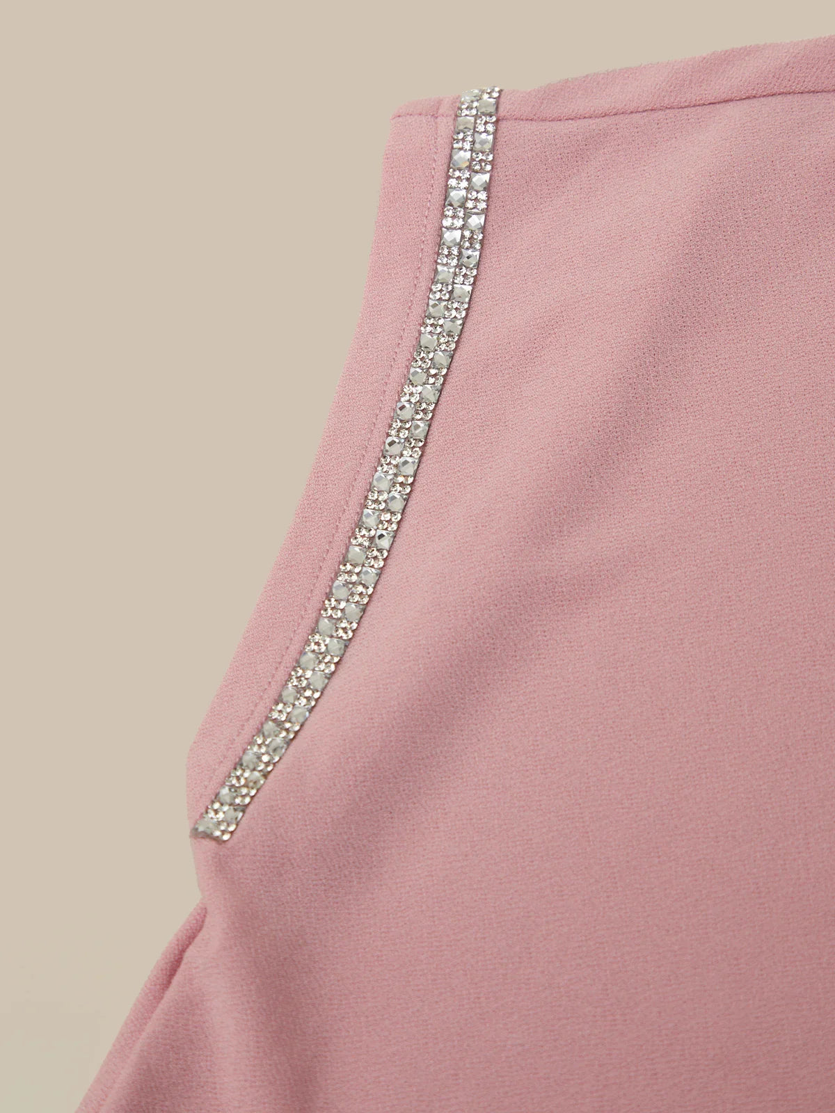 Pink garment with a decorative silver trim on a beige background