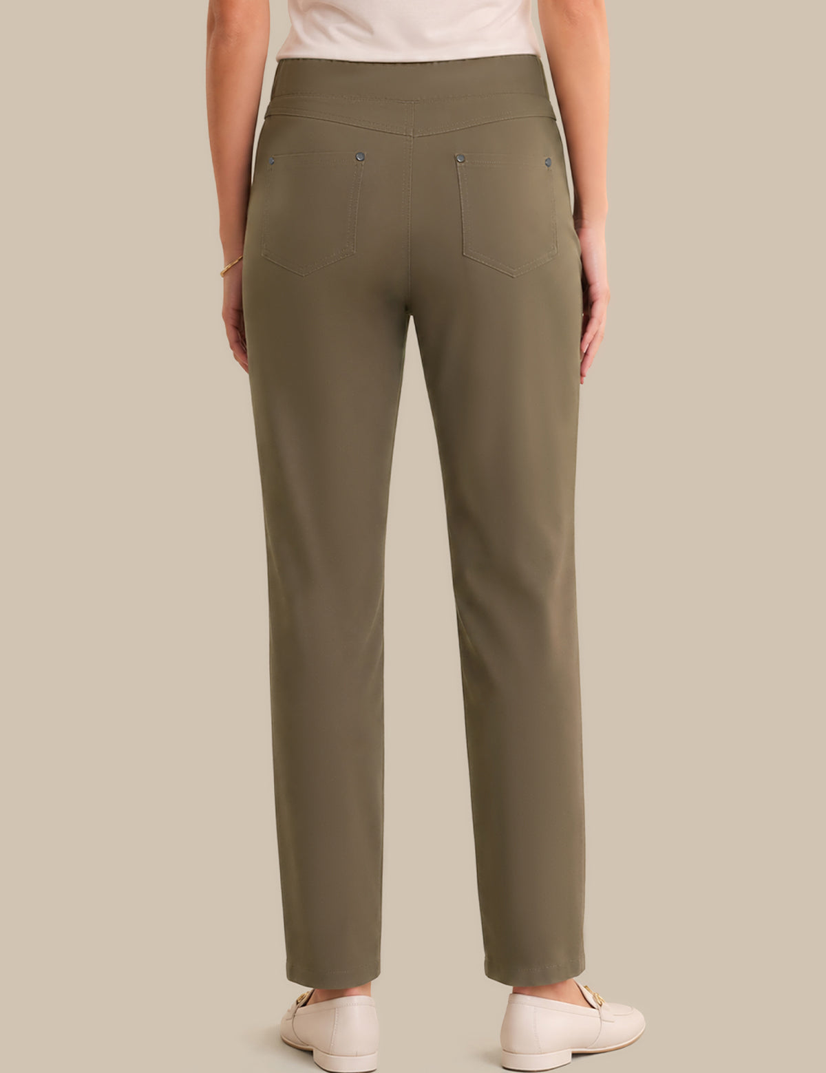 A person shown from the back wearing straight-leg olive green trousers, paired with a light top and white shoes, against a solid beige background.