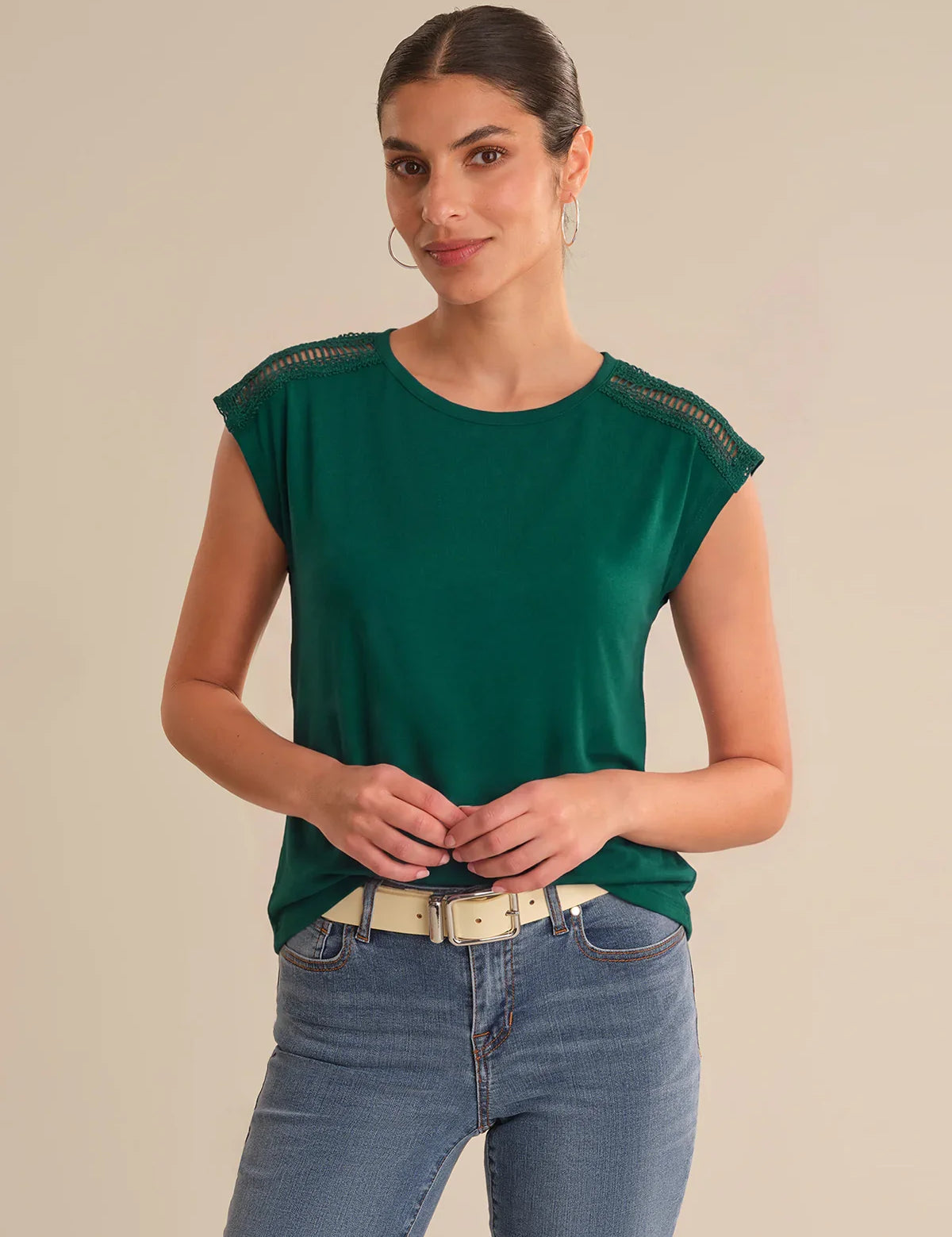 Woman wearing a green top with lace details on a beige background