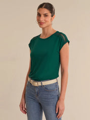 Woman wearing a green top and blue jeans against a beige background