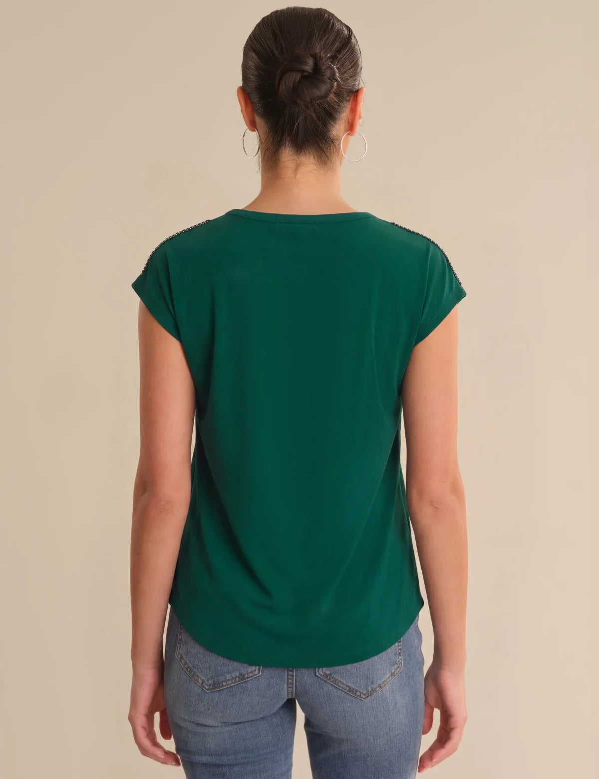 Person wearing a green t-shirt and blue jeans on a beige background