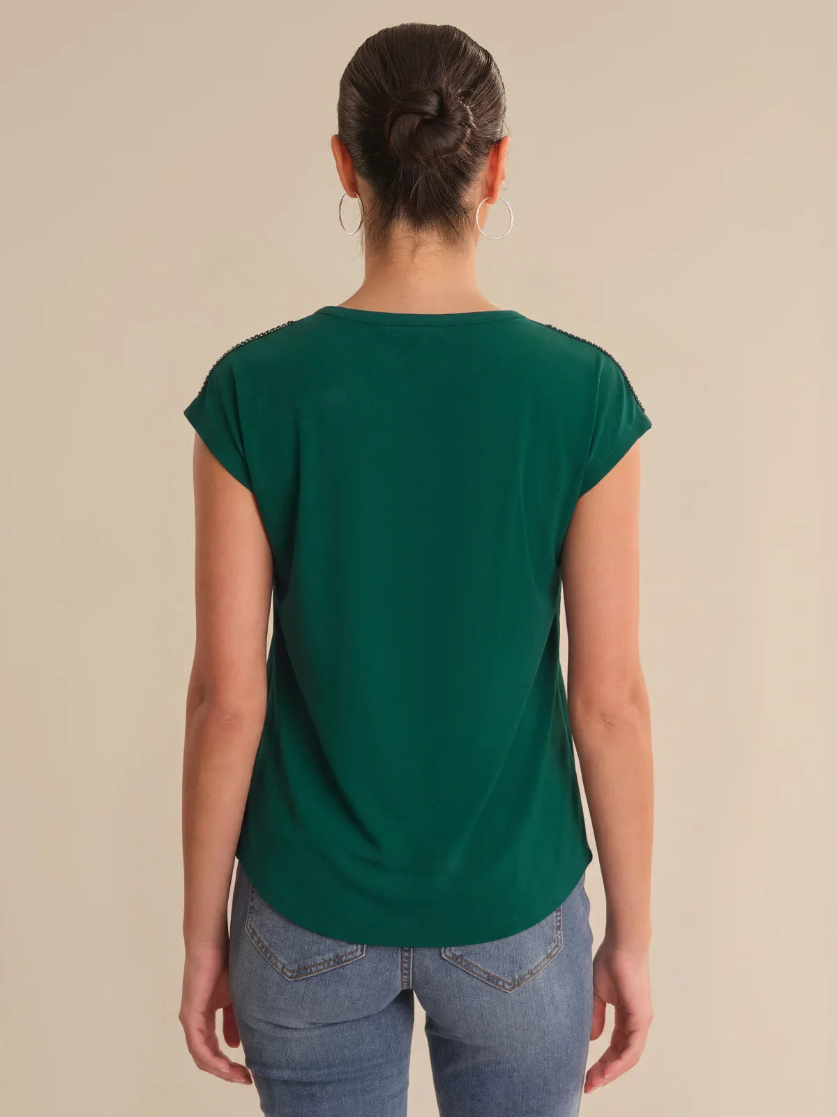 Person wearing a green t-shirt and blue jeans on a beige background