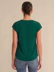 Person wearing a green t-shirt and blue jeans on a beige background
