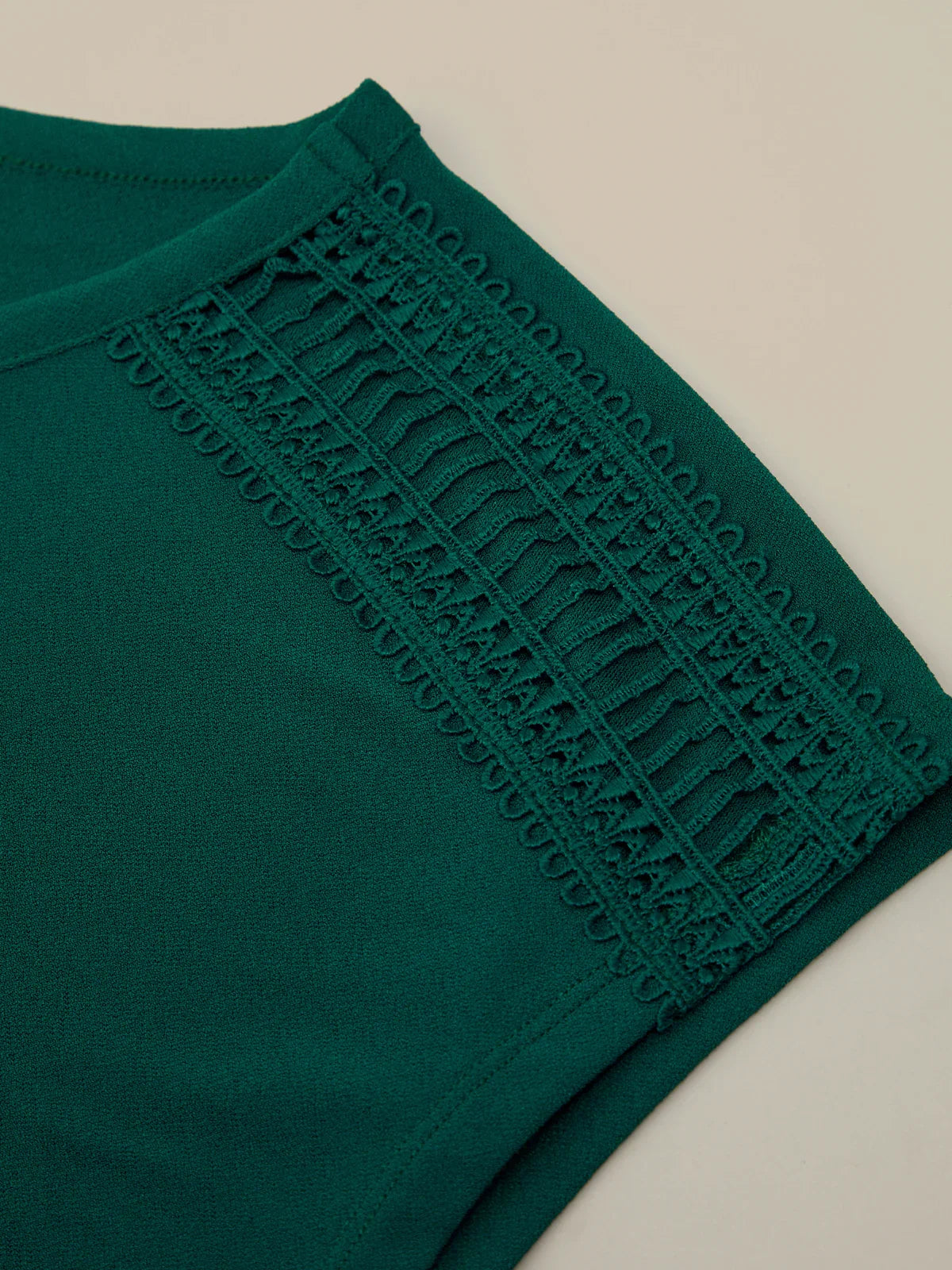 Green garment with lace detailing on a beige background