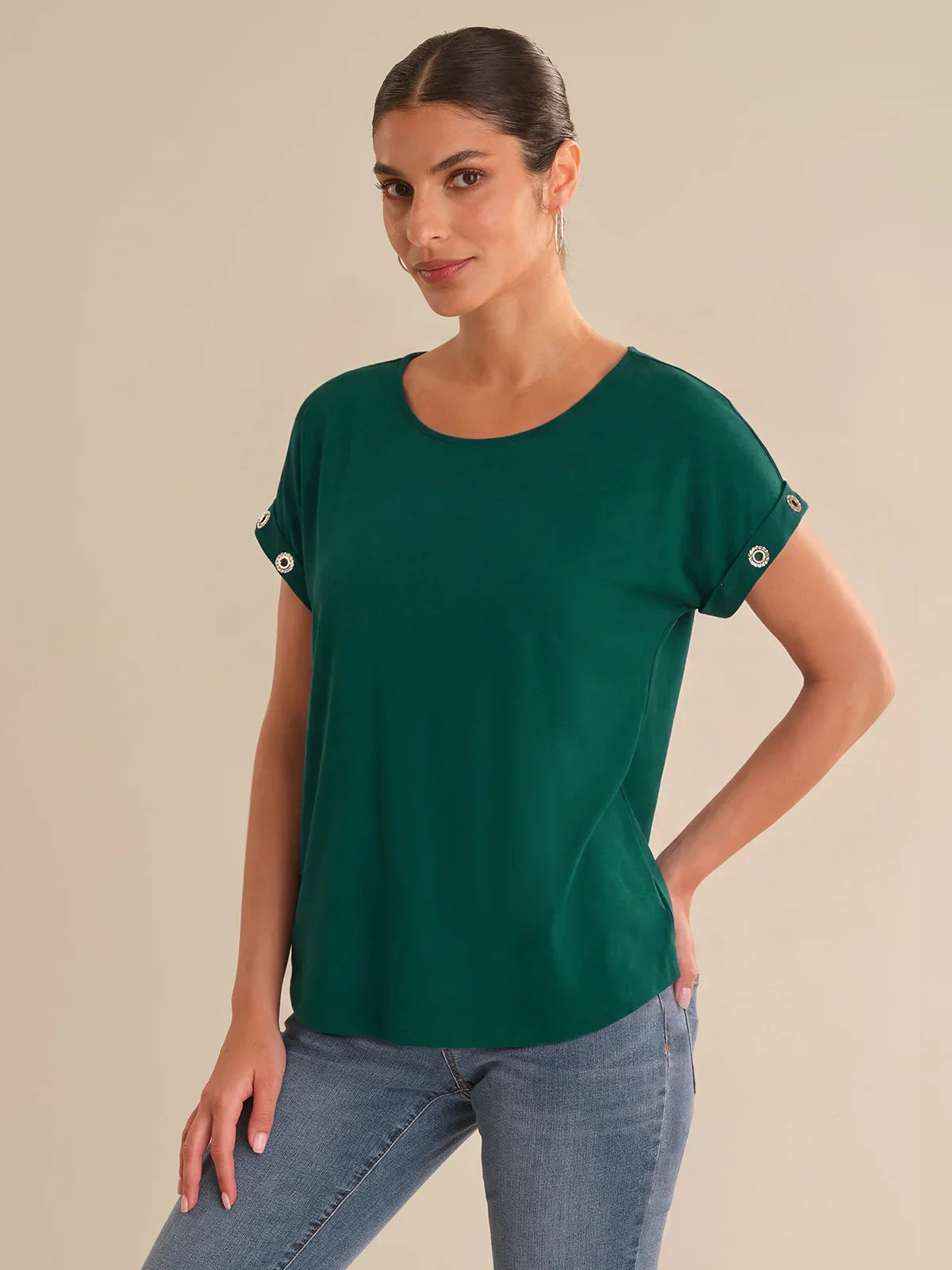 Woman wearing a green top with button details on a beige background