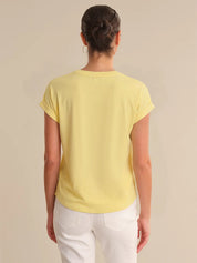 Person wearing a yellow t-shirt and white pants on a beige background