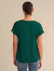 Person wearing a green top with button details on a beige background