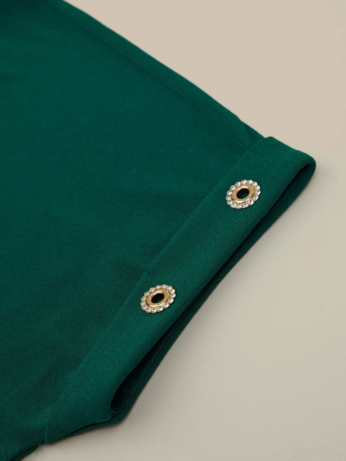 Green fabric with decorative eyelets on a beige background