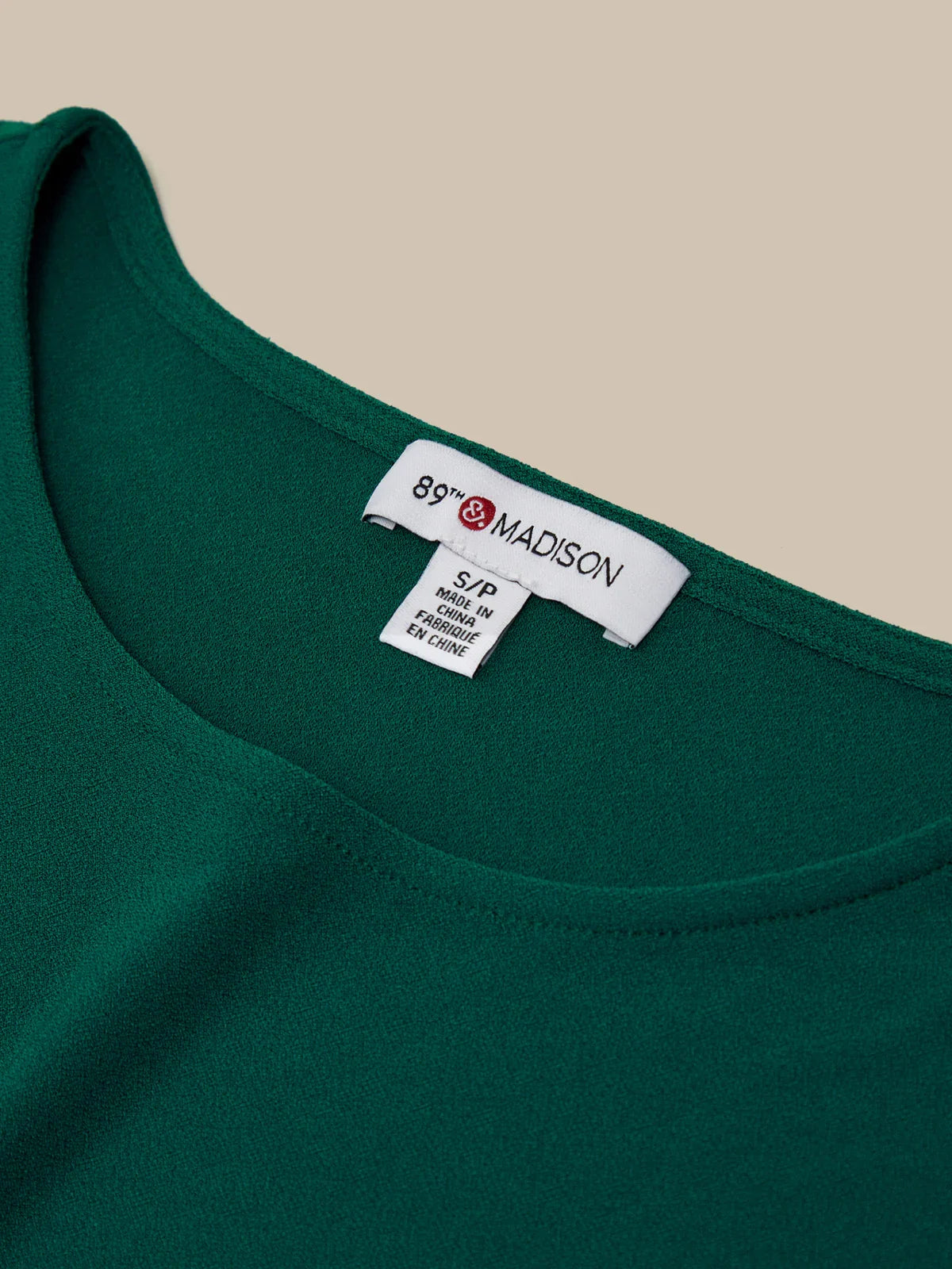 Green garment with a label on a beige background