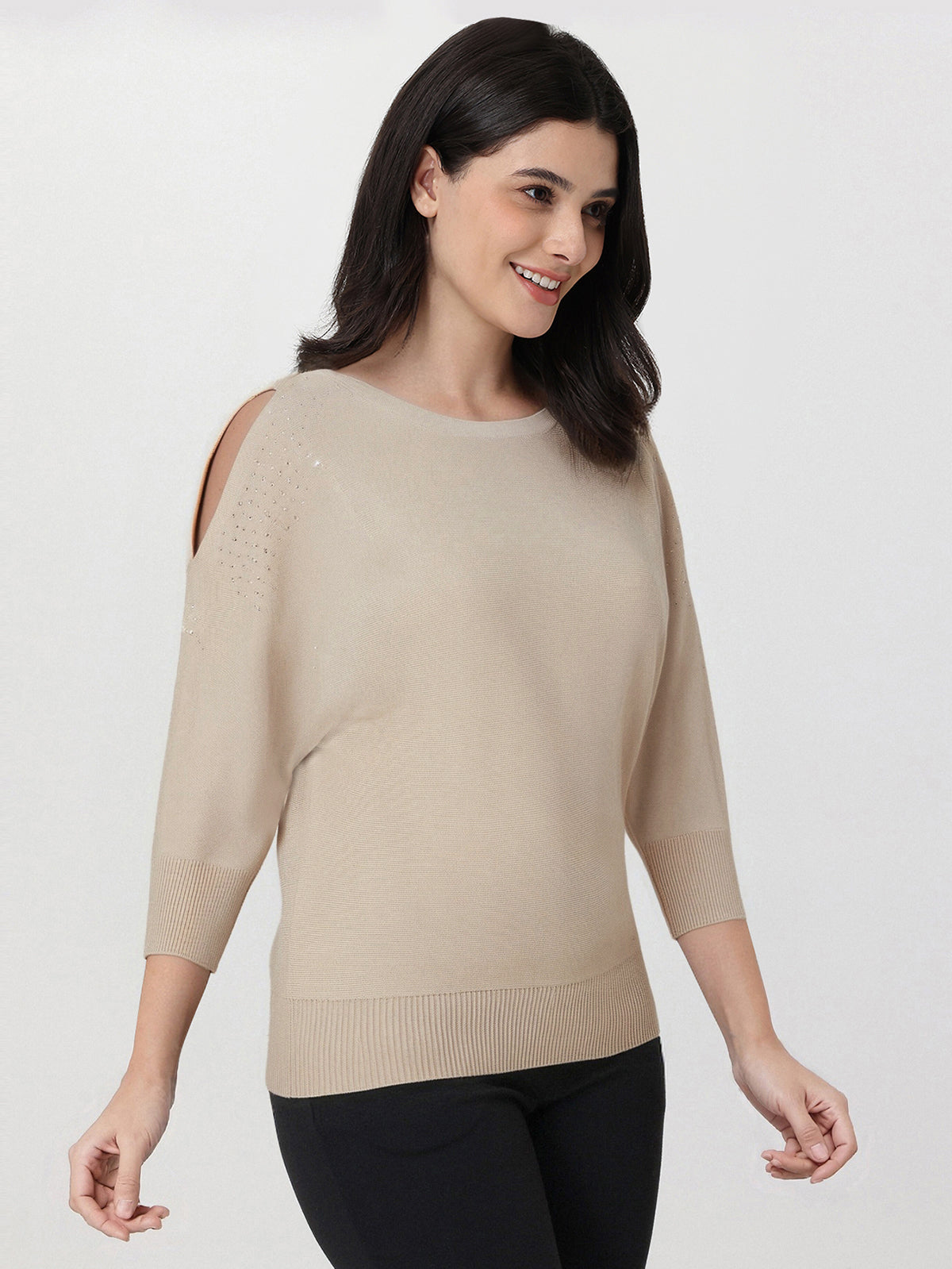 Woman wearing a beige sweater with cut-out shoulders on a white background