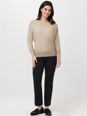 Woman wearing a beige sweater and black pants on a white background