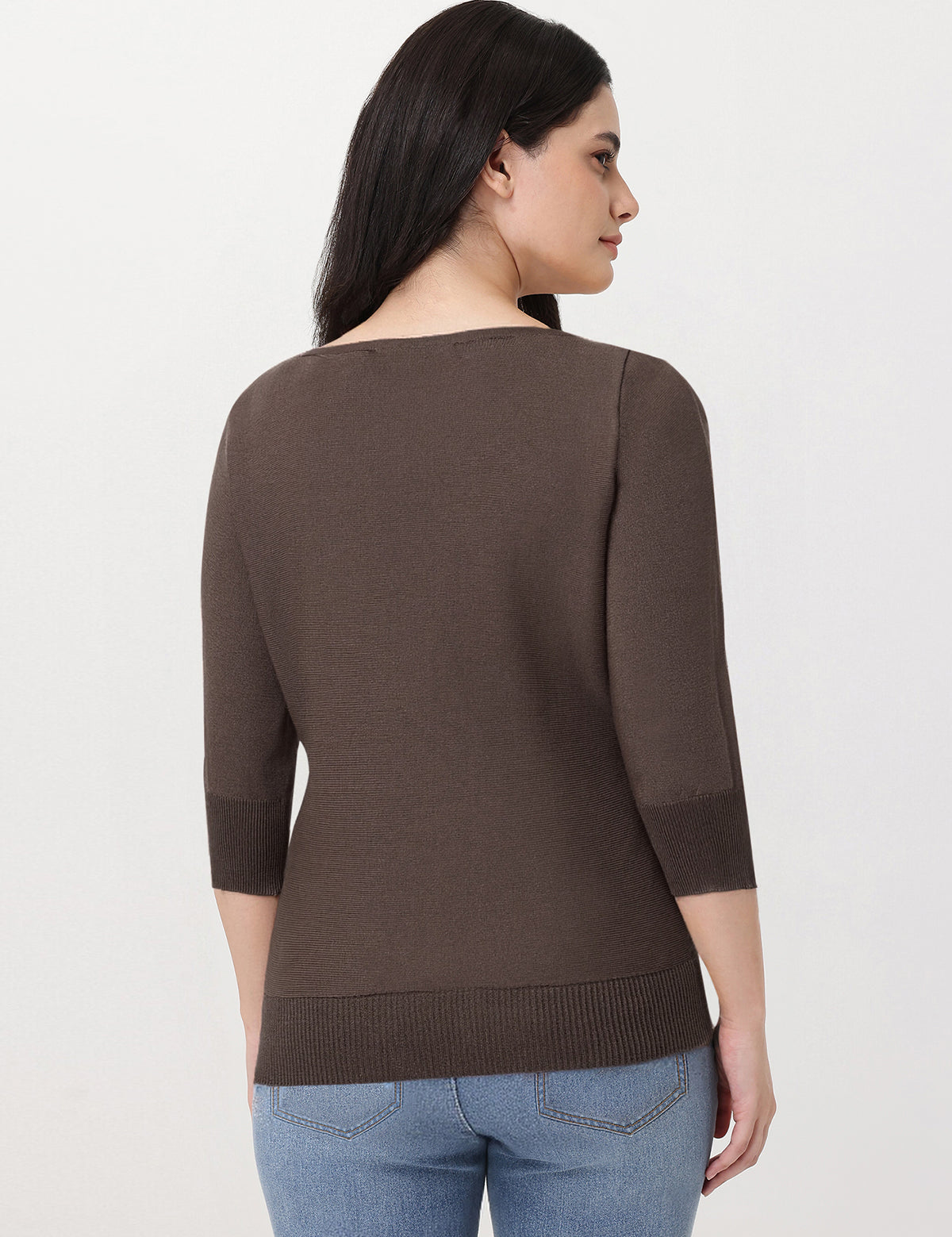 Woman wearing a brown sweater and blue jeans on a white background