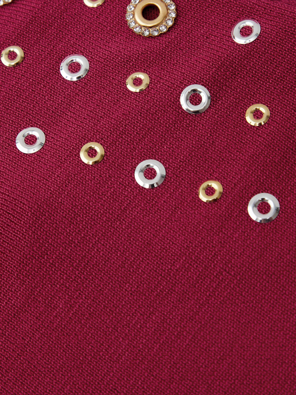 Close-up of a red fabric with gold and silver grommet
