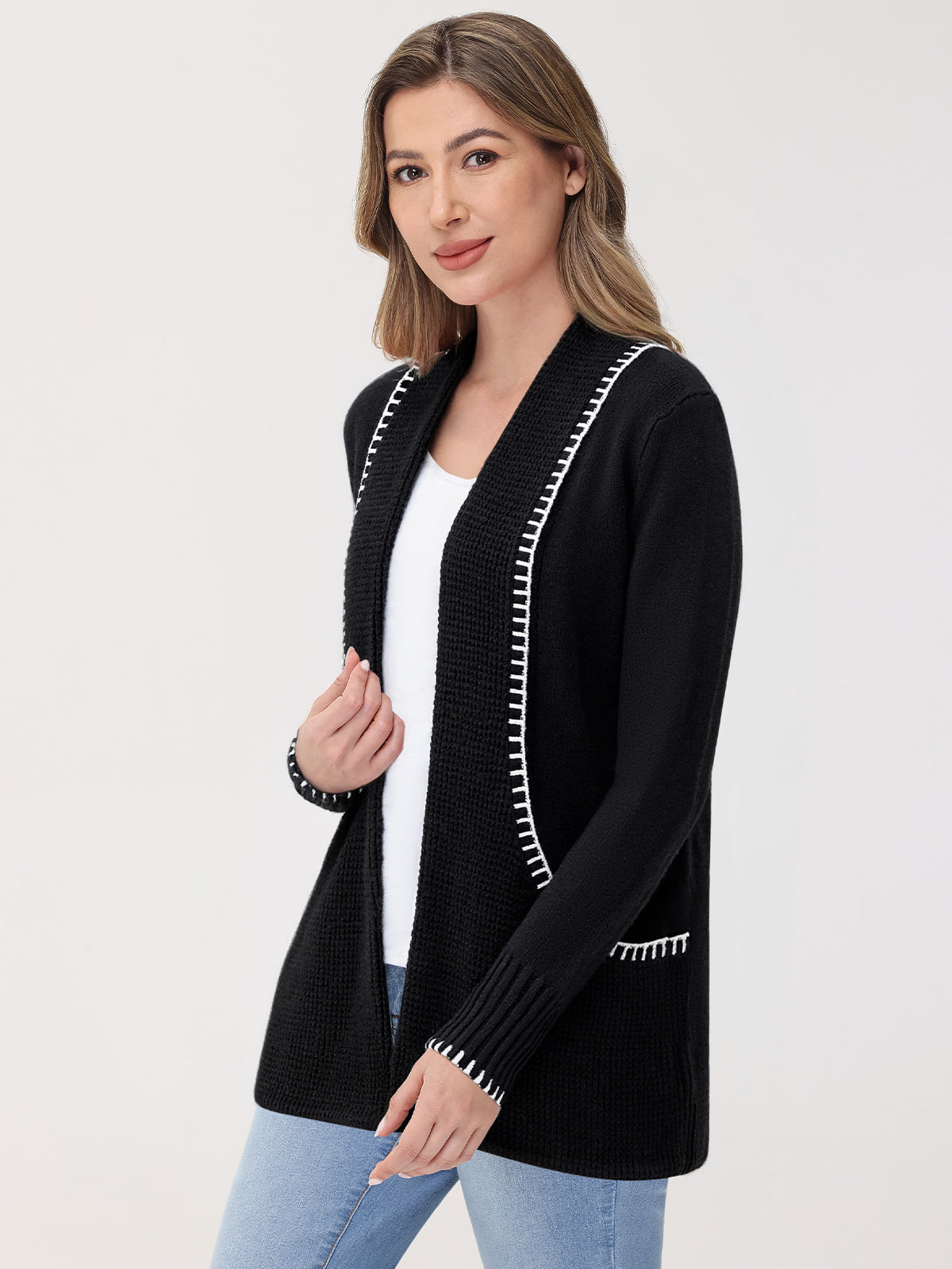 Woman wearing a black cardigan with white trim on a plain background