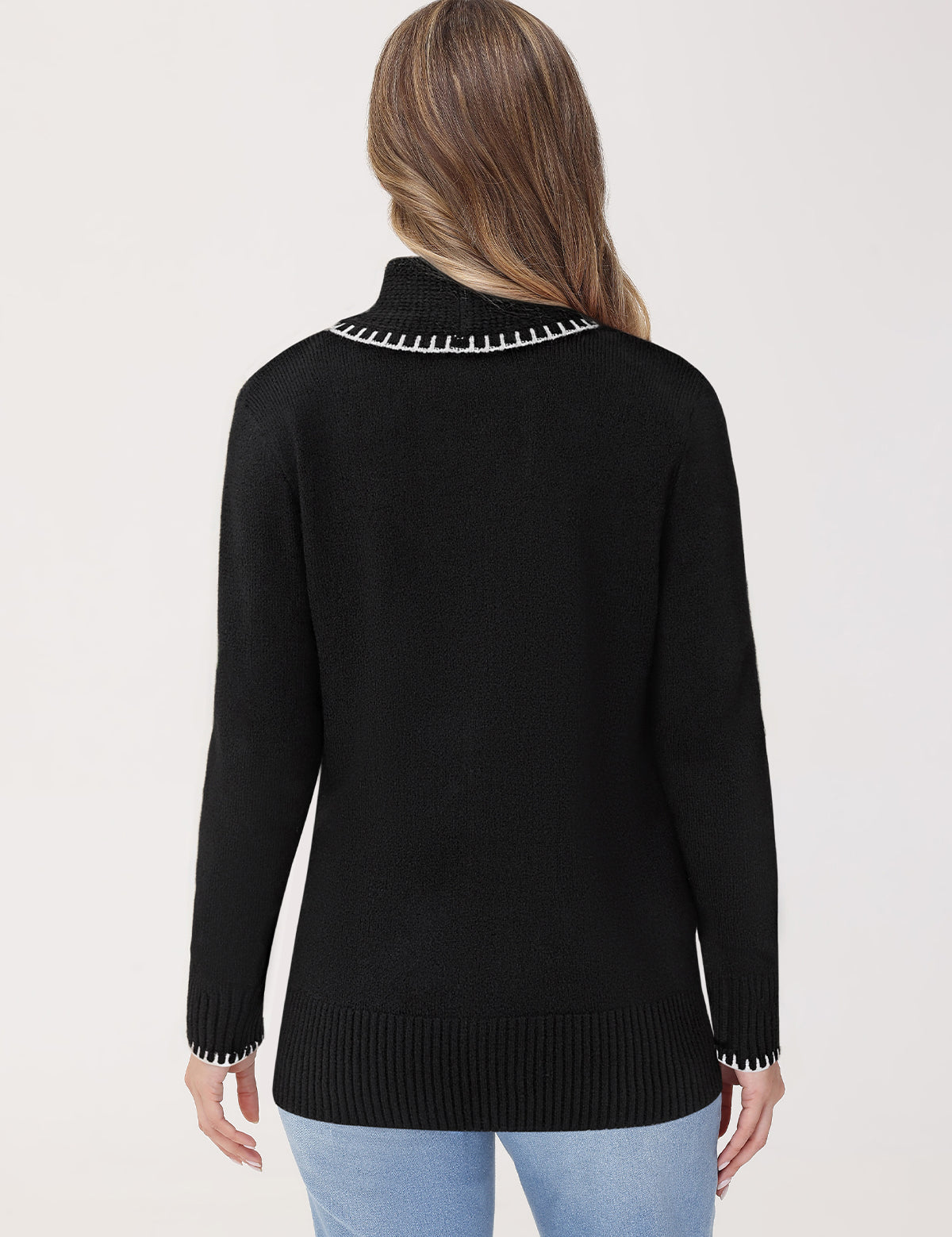 Black sweater with white trim worn by a person on a light gray background