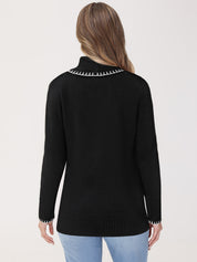 Black sweater with white trim worn by a person on a light gray background